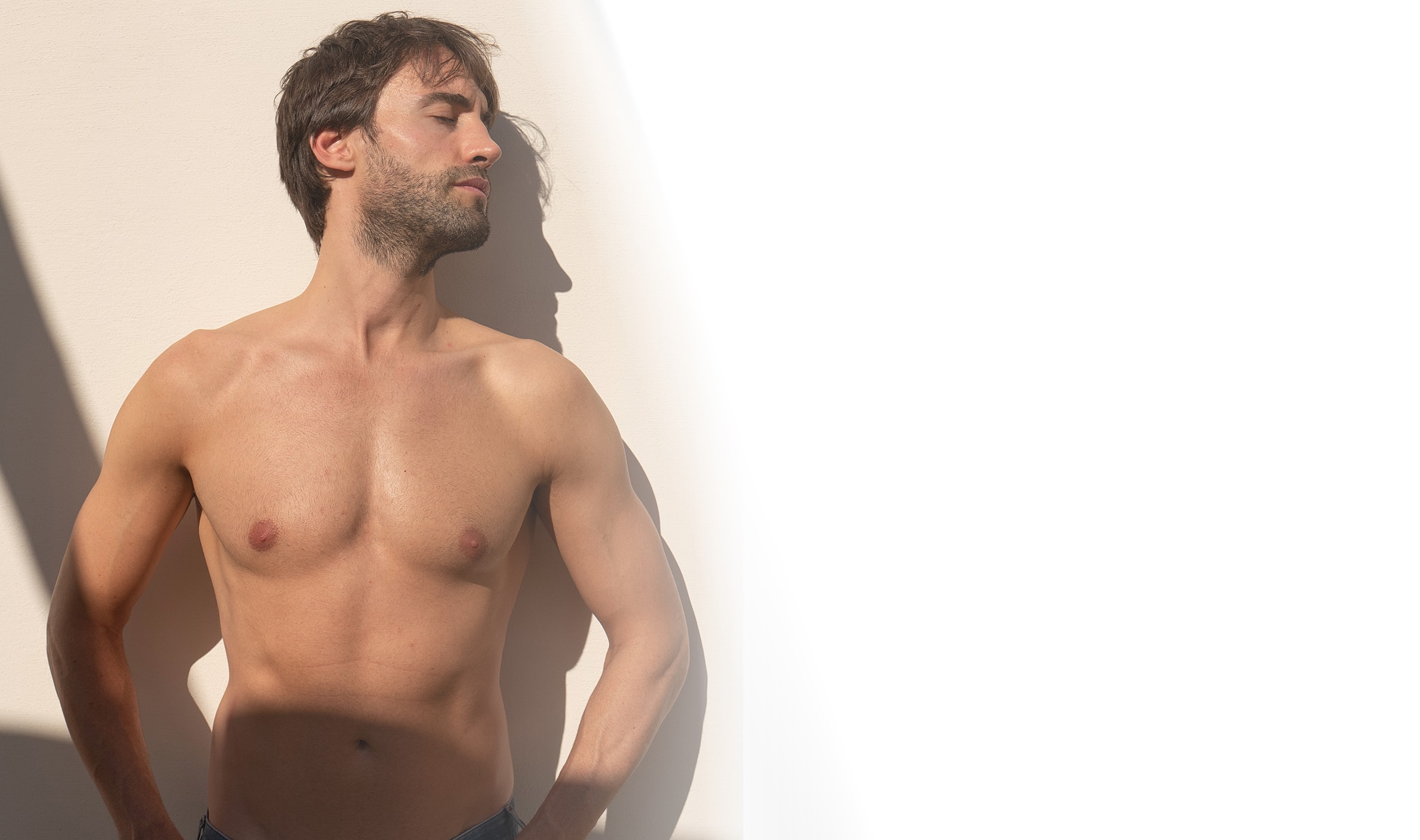 Man leaning against wall in sunlight.