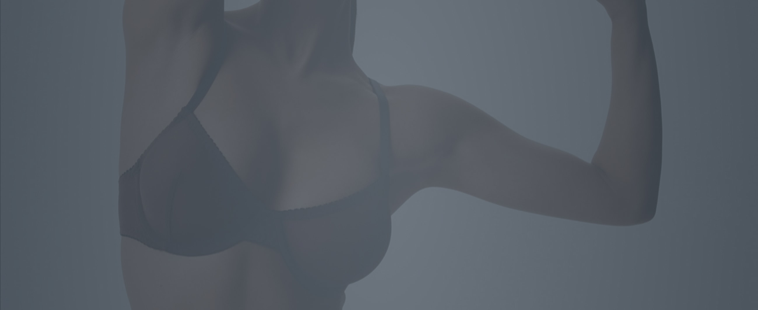 Woman flexing arm in dark lingerie setting.