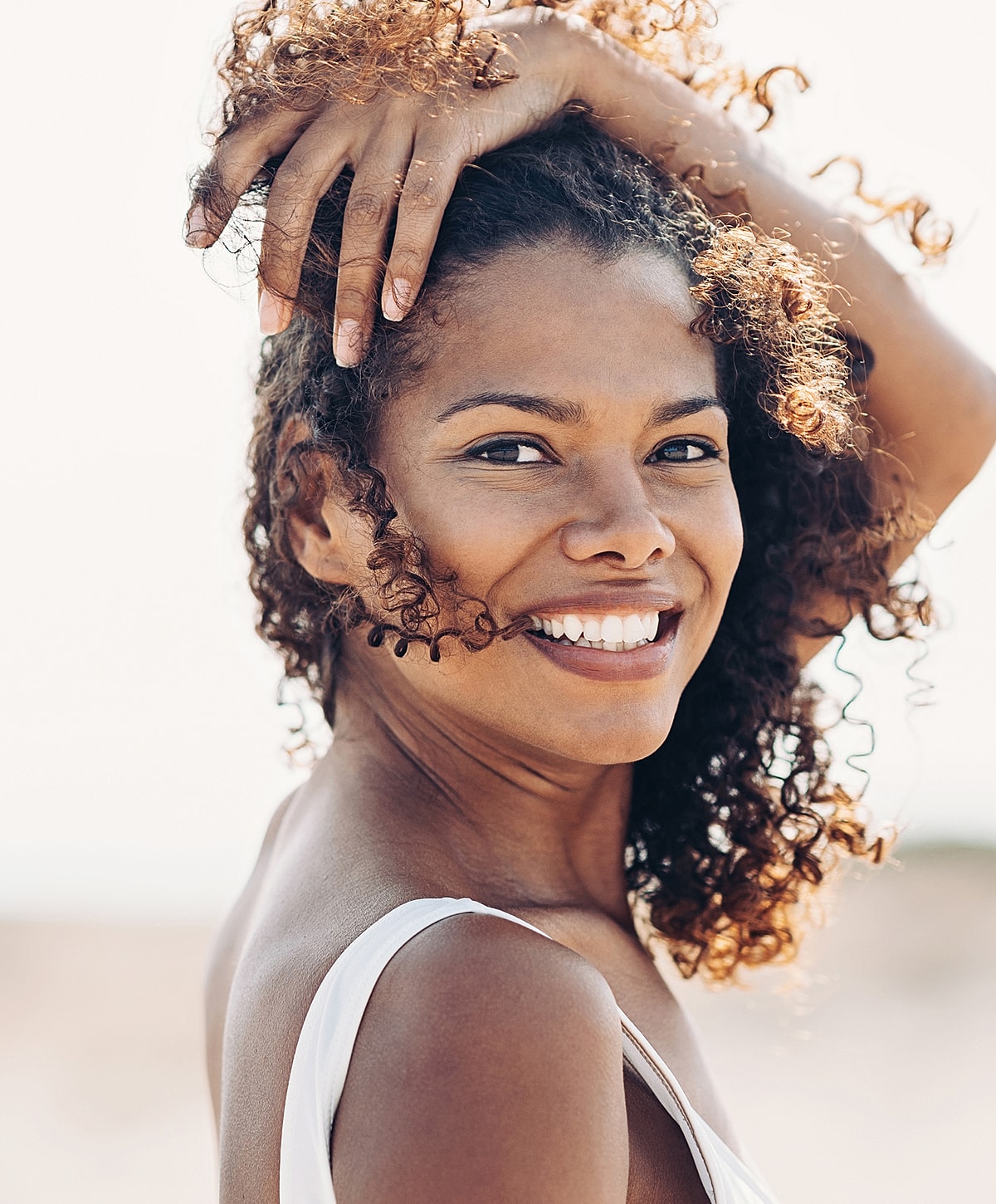 Smiling woman with curly hair outdoors.