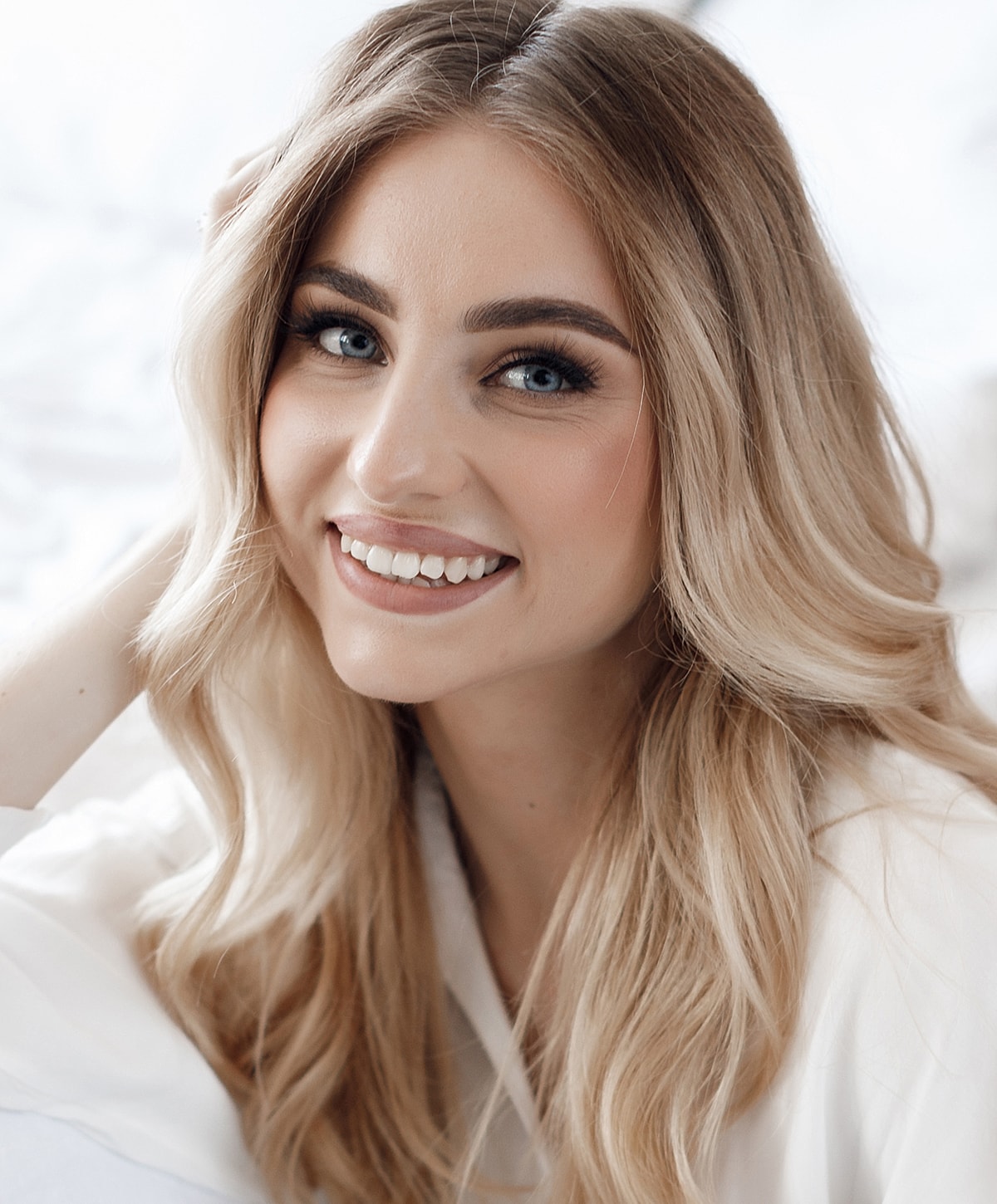 Smiling woman with wavy blonde hair indoors.