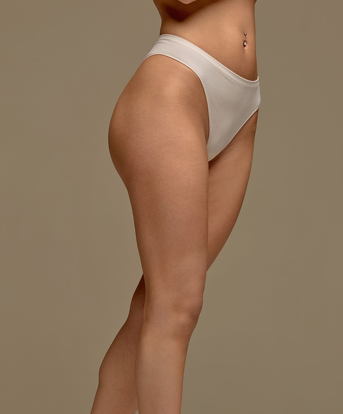 Model wearing beige high-waisted underwear against backdrop.
