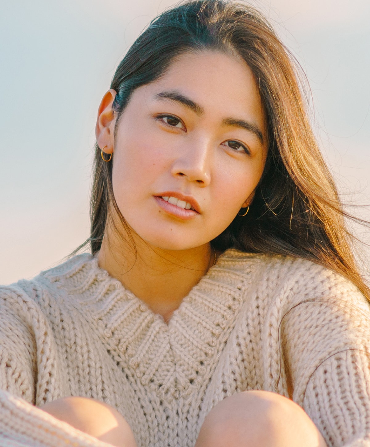 Woman in a cozy sweater, serene expression.
