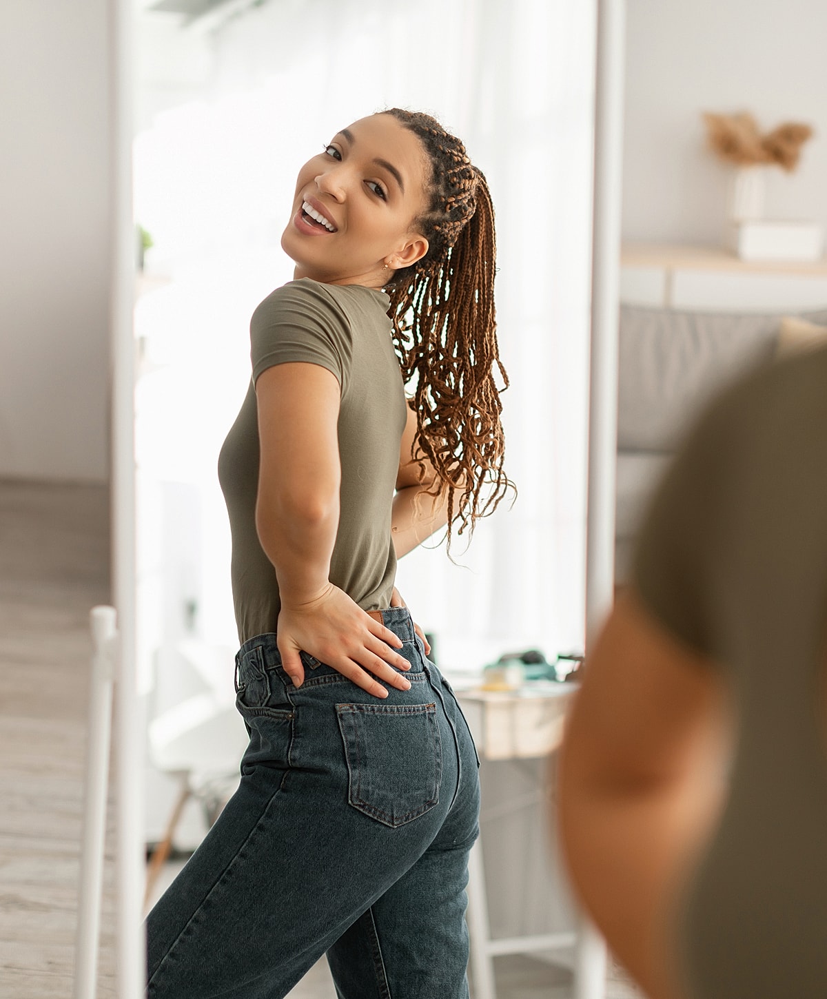 Smiling woman poses in front of mirror.