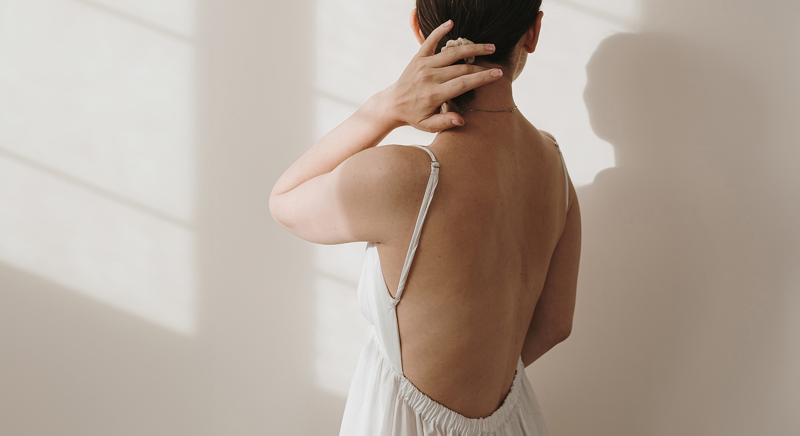Woman in backless dress, soft lighting, elegant pose.