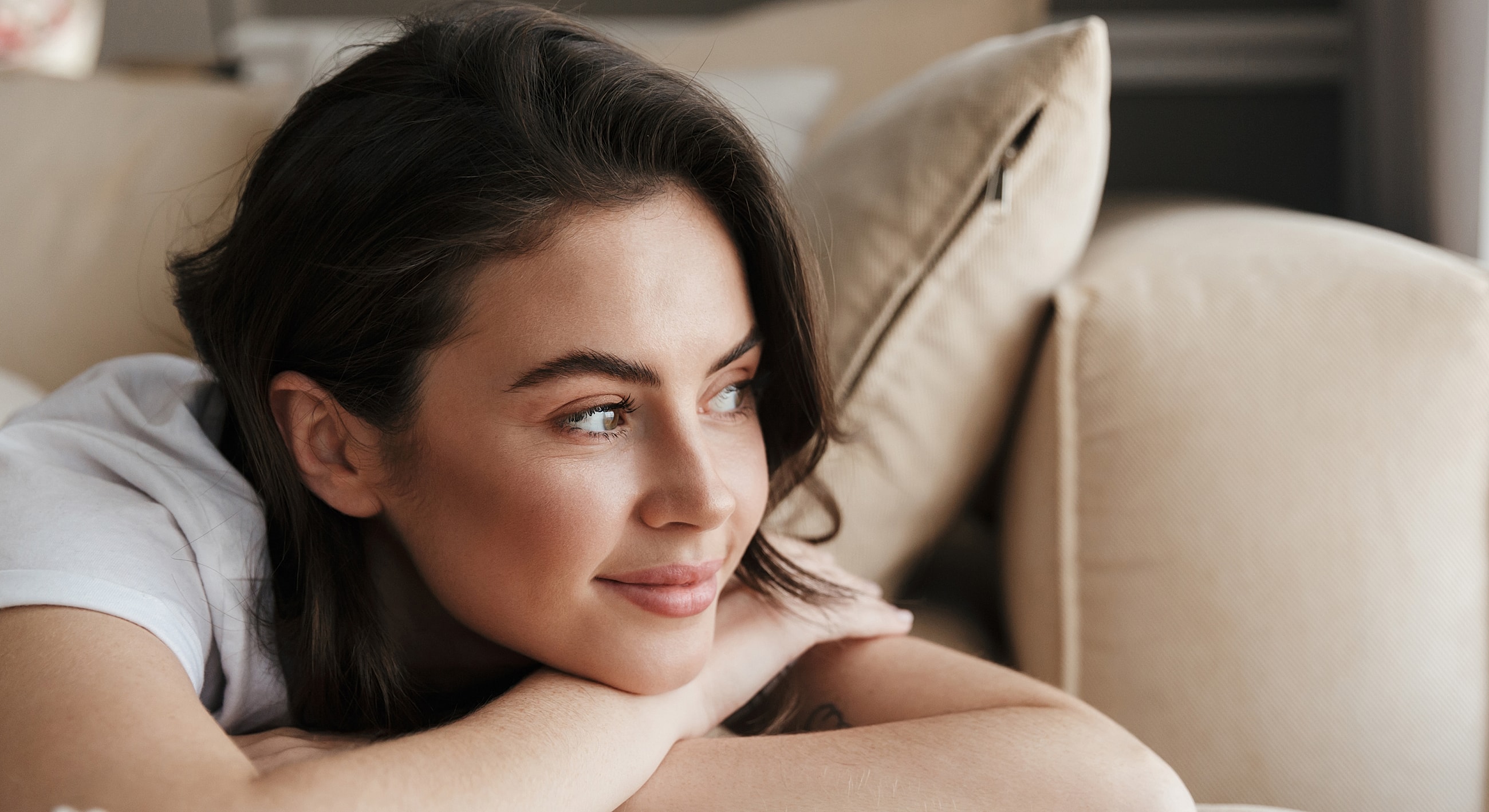 Woman resting her head on arms, thoughtful expression.