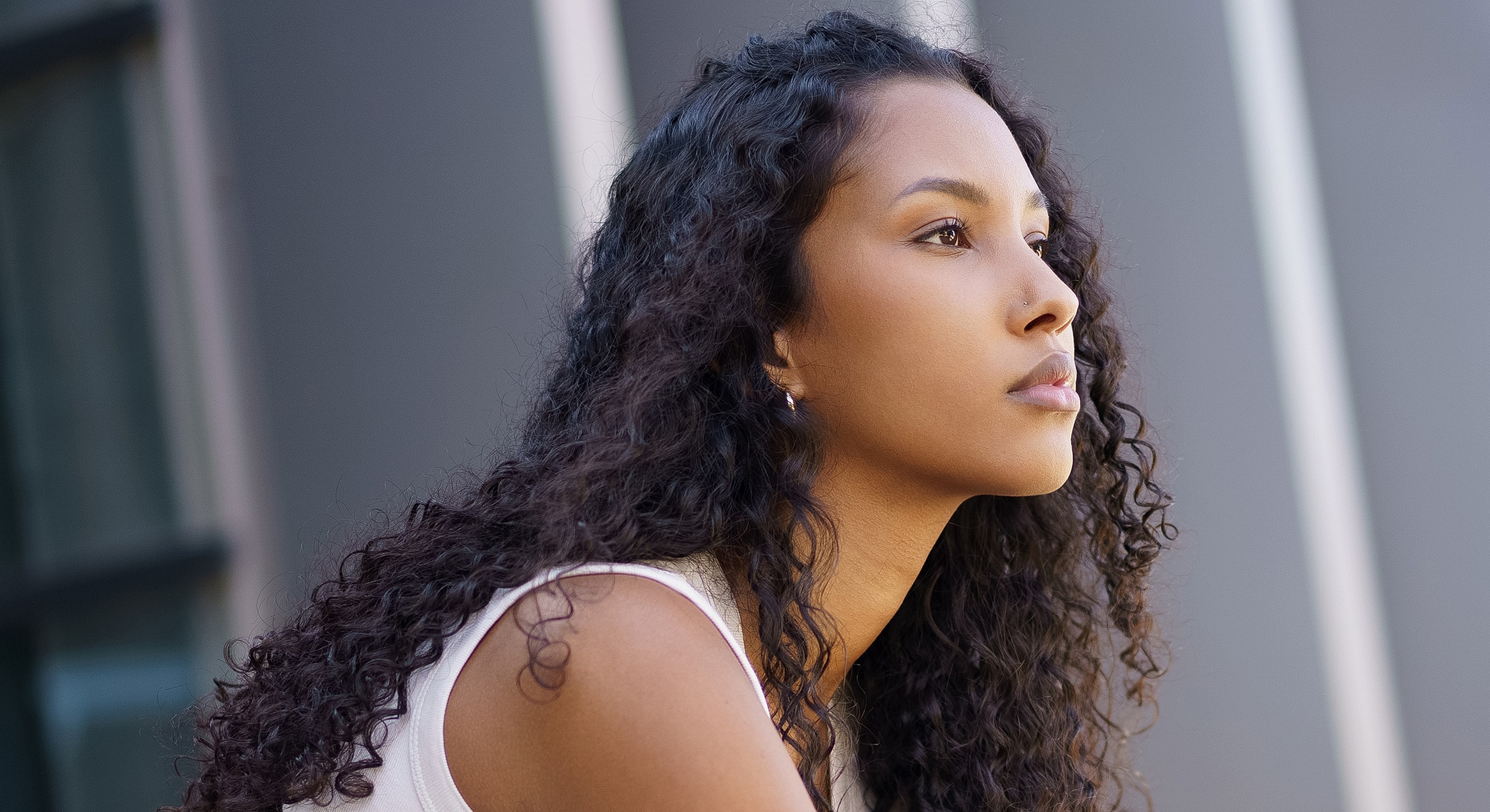 Woman with curly hair looking thoughtfully upward.
