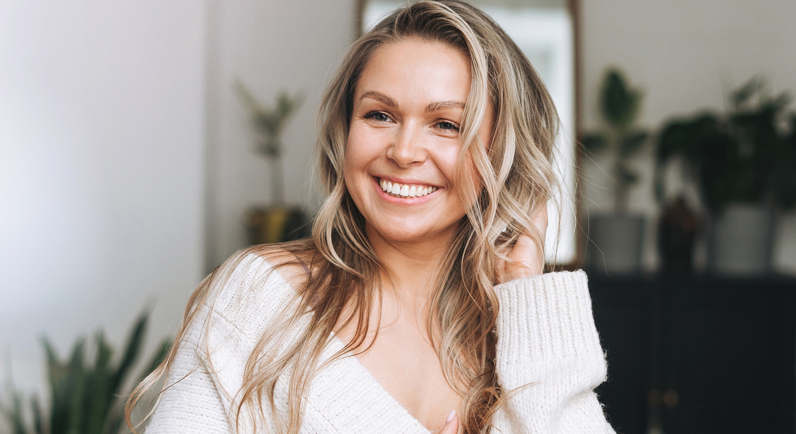 Smiling woman in cozy sweater indoors.