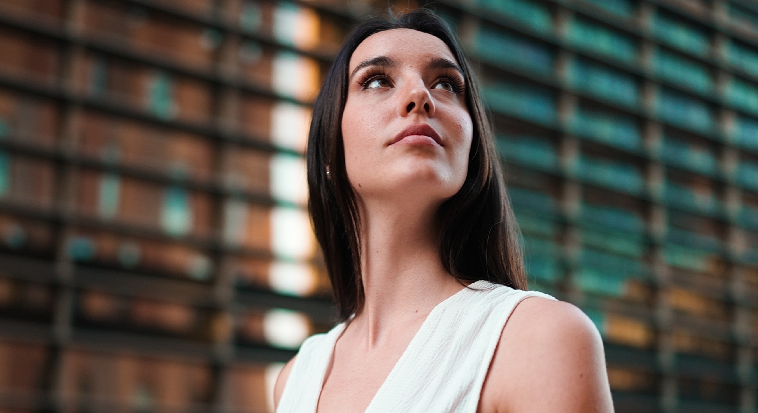Young woman looking upward in urban setting.